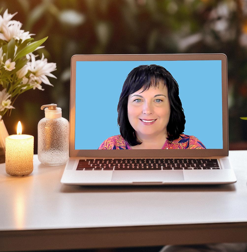 Cozy home desk space with flowers and a lit candle. Eileen is on the laptop screen.