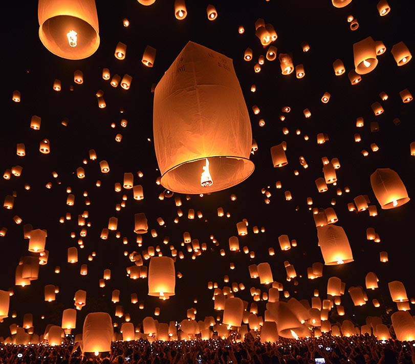 Hundreds of orange paper lanterns rise into the sky